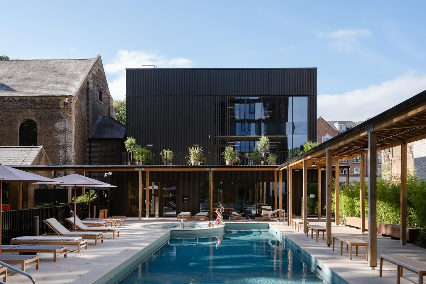 The outside area of The Brentford Project, known as the Resident's Cub, with a pool, outdoor area and an oak timber-covered walkway.