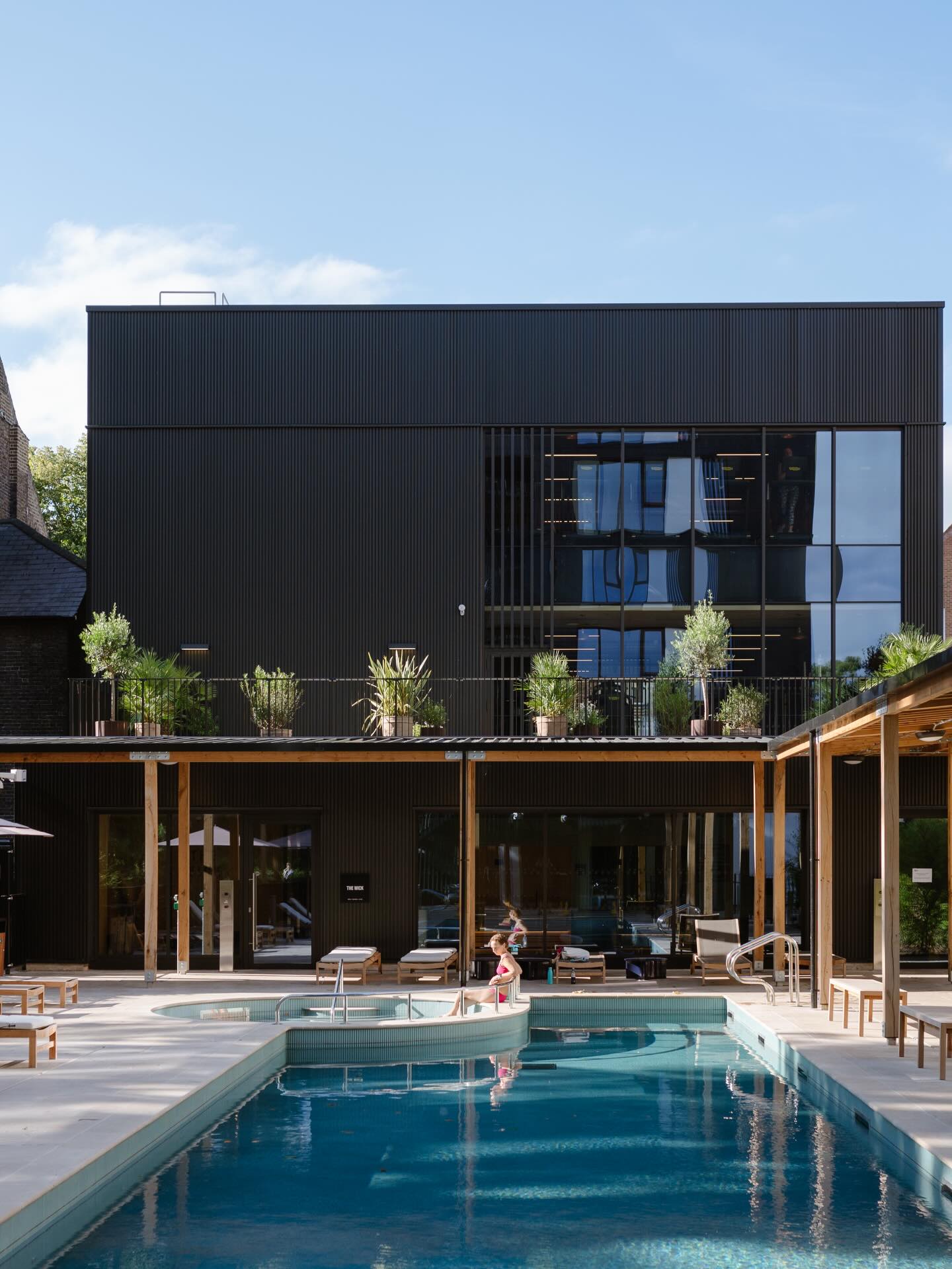 The outside area of The Brentford Project, known as the Resident's Cub, with a pool, outdoor area and an oak timber-covered walkway.