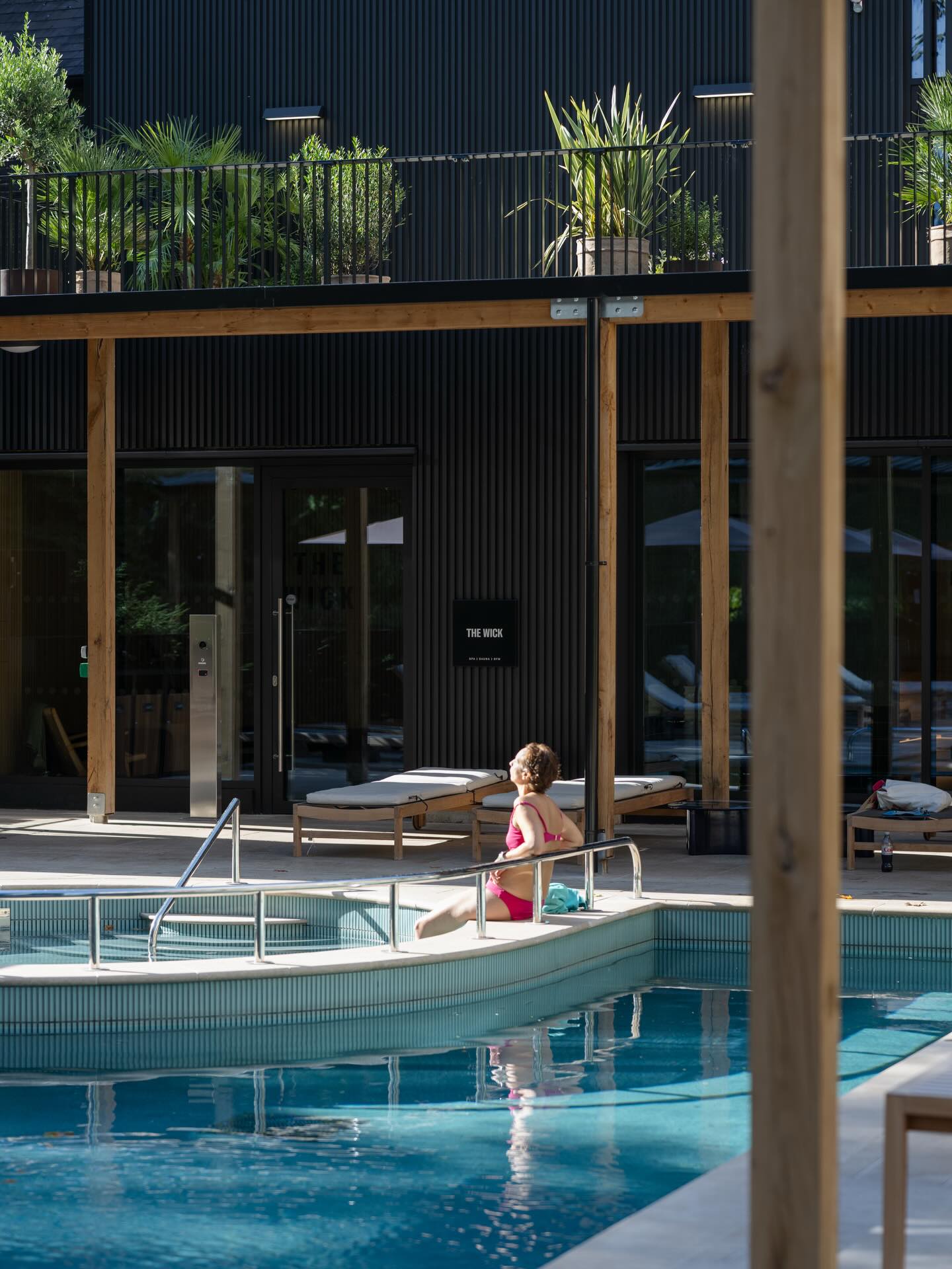A person sitting in the pool in the outdoor area of the Resident's Club at The Brentford Project, known as 