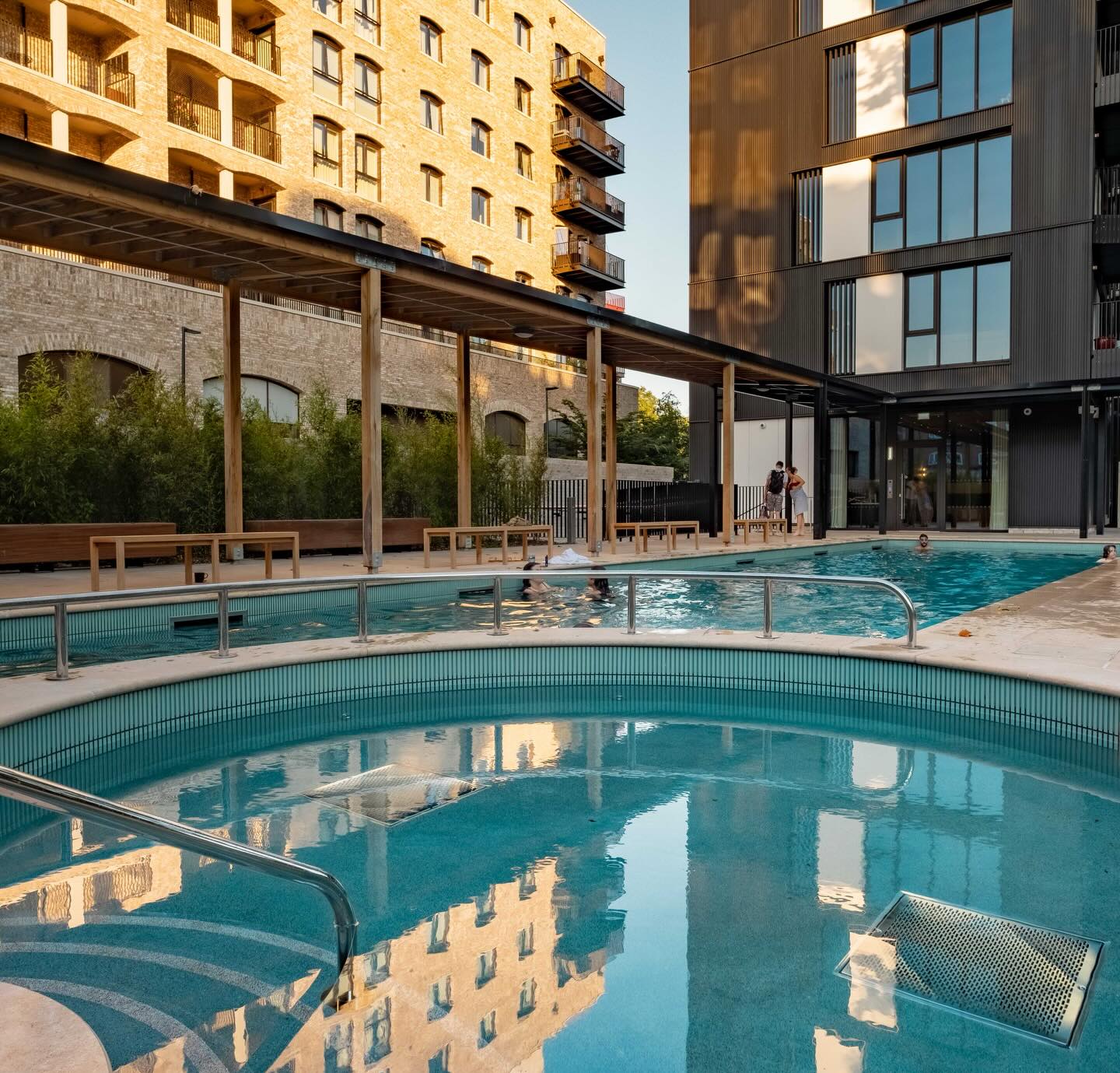 The pool and the outdoor area of The Wick at the Brentford Project. The building and timber-covered walkway are in the background.